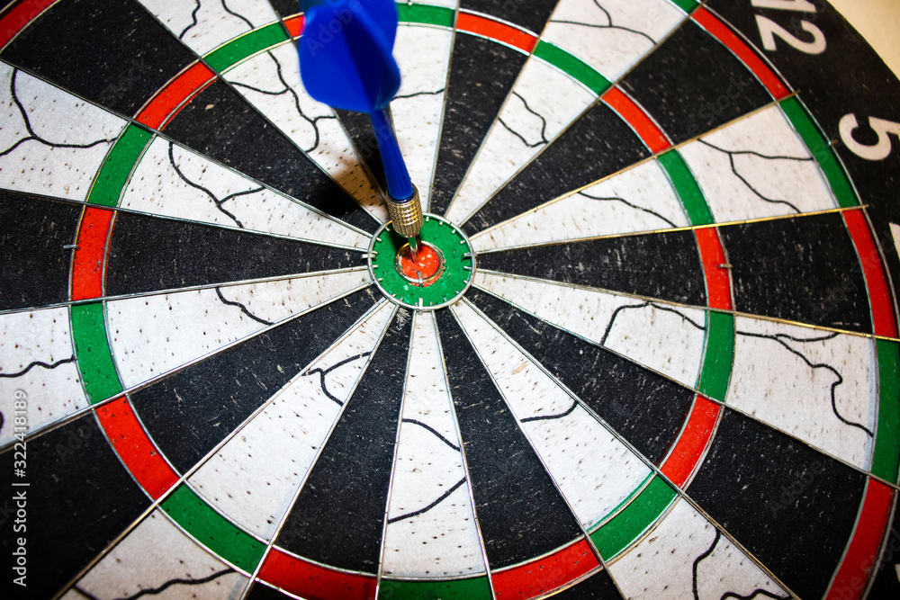 Red dart arrow hitting in the target center of dartboard Red dart arrow hitting in the target center of dartboard