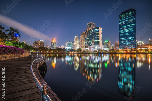 Skyscrapers and Lake with Wooden Walk Way in City Park. View of Benjakiti Park at Night. Beautiful Night Scene of Public Park in Bangkok, Thailand, Asia. photo