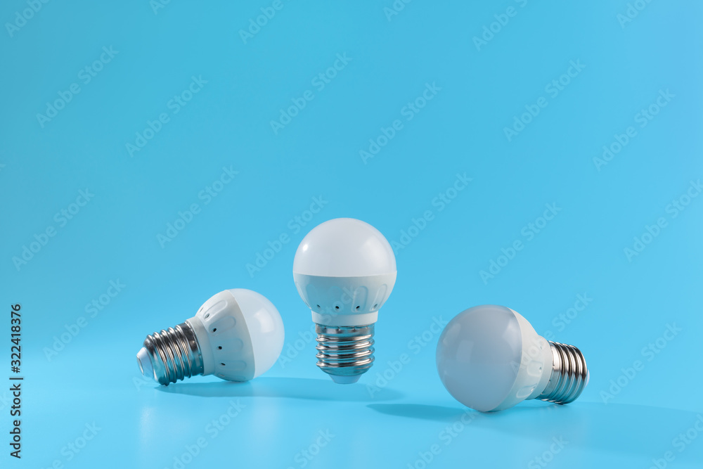 Three small white led energy saving led light bulbs on a blue background. Three small white led energy saving led light bulbs on a blue background.