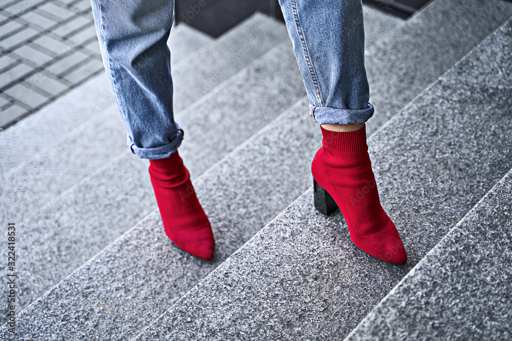Woman legs in red sexy trendy stretch knitted fabric pointed toe block heel sock boots shoes and blue denim jeans pants Woman legs in red sexy trendy stretch knitted fabric pointed toe block heel sock boots shoes and blue denim jeans pants