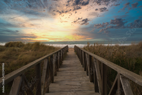 Wooden path and sunset on the beach of El Palmar, near the Caños de Meca, an ideal place to spend a great holiday on the coast of the province of Cadiz, in Andalusia, Spain photo