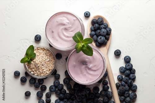 two blueberry yogurt in glasses on a white table, top view, ingredients for cooking diet food