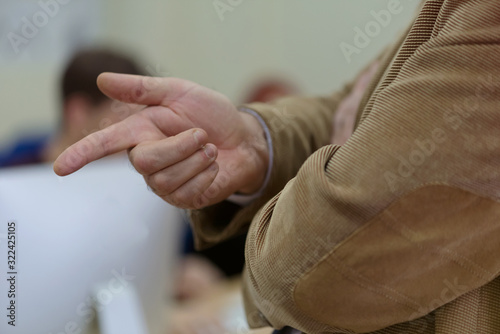 IT technologies teacher at work. IT professor explain lesson to multietchnic students. Professor's hand with gesture.
