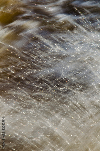 Texture of fast moving water, in yellowish tones.