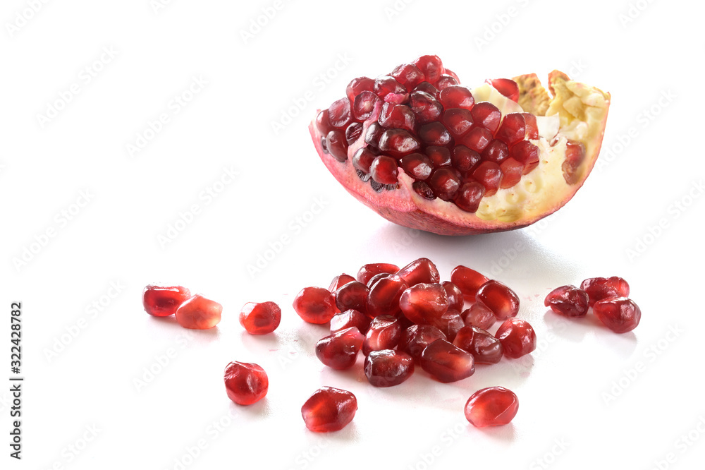 Piece of a pomegranate fruit with red juicy seeds isolated with shadows on a white background, copy space Piece of a pomegranate fruit with red juicy seeds isolated with shadows on a white background, copy space