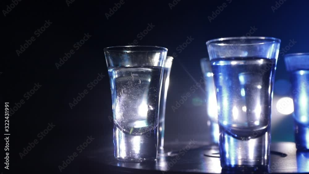A beautiful carafe with vodka stands on a wooden table with glasses. Dramatic toned foggy background with light. Selective focus. Club drink concept. A beautiful carafe with vodka stands on a wooden table with glasses. Dramatic toned foggy background with light. Selective focus. Club drink concept.
