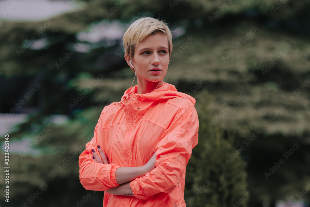 Smiling sports woman with headphones outdoors. looking away