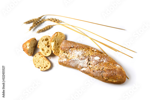 Baguette or French bread baked with onions half sliced and some wheat ears isolated with shadows on a white background, copy space, high angle view from above