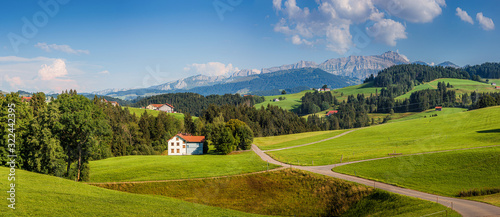Beautiful view of idyllic mountain scenery in the Alps with green meadows and famous Saentis summit in the background on a sunny day with blue sky and clouds in summer, Appenzellerland, Switzerland photo