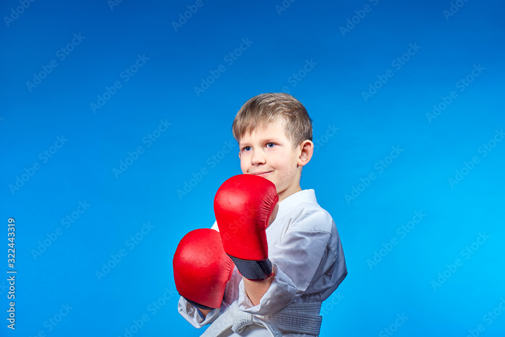 On a light blue background, an athlete boy with red overlays on his hands On a light blue background, an athlete boy with red overlays on his hands