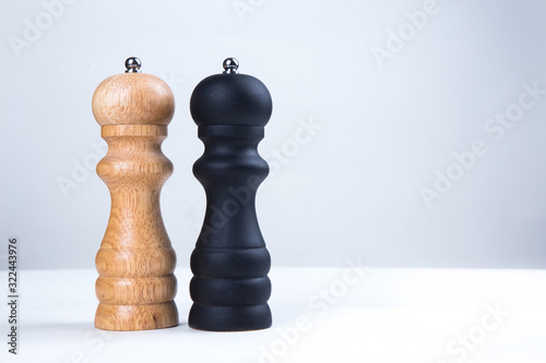 salt and pepper wooden shakers, grinders on a white table with white background 