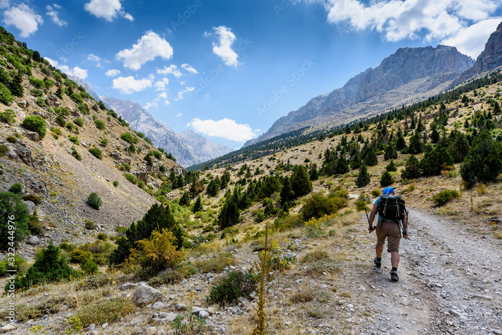 Turkey, Chamard - August 3, 2019: Tourist walk along the road through the mountain landscape in the Turkish national Park aladag in summer day, view from the back