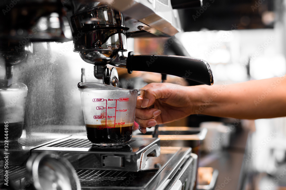 Coffee in measuring cup on a coffee machine