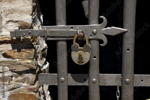 padlock on old medieval gate with metal bars