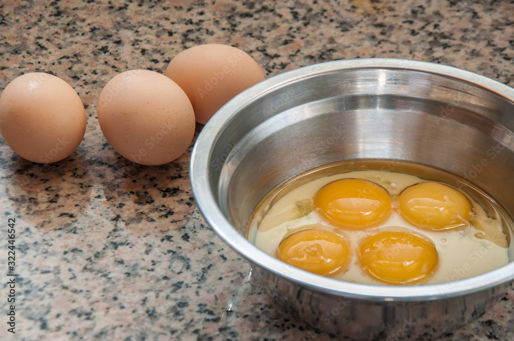 Close-up of Egg and egg yolk. Egg yolk in the stainless steel container. Close-up of Egg and egg yolk. Egg yolk in the stainless steel container.