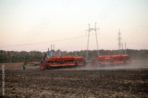 Agricultural mechanical seeders of grain crops. Tactor with a seeder sows grain in the field. A farmer on a tractor with a seeder processes the field.