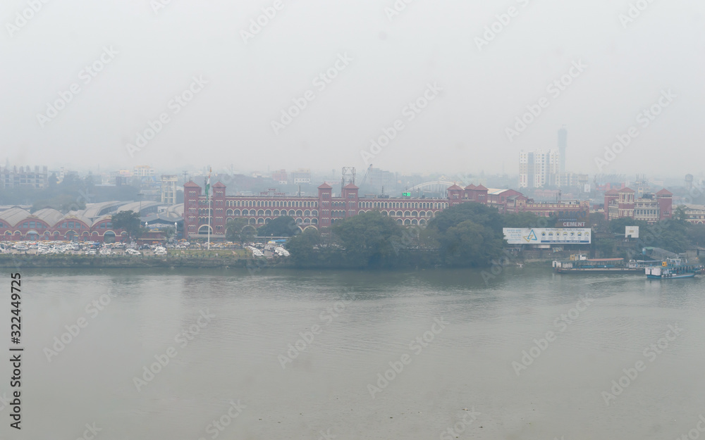 Panoramic Howrah Railway Transportation Station Building Aerial view landscape from Hooghly riverside riverbank area on foggy winter evening day. Kolkata West Bengal India South Asia Pac January 2020 Panoramic Howrah Railway Transportation Station Building Aerial view landscape from Hooghly riverside riverbank area on foggy winter evening day. Kolkata West Bengal India South Asia Pac January 2020