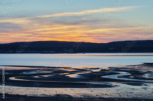 Zigzag shape tidal marks on sunset and mountain on the background.