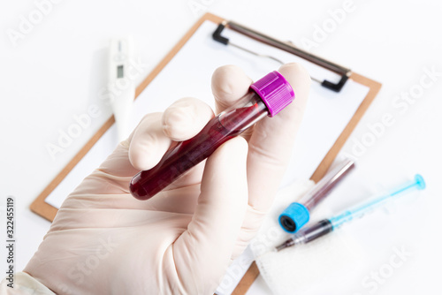 Doctor holding blood test over spreadsheet for analysis.