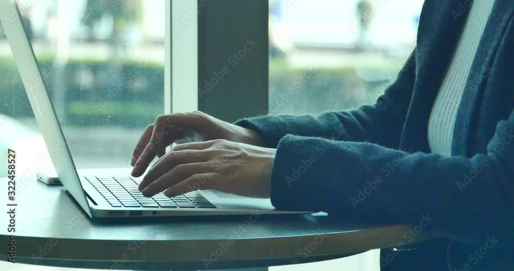 4k silhouette of female working on laptop computer in coffee shop desk,city pedestrian and traffic window view,business correspondence using a laptop,keyboard input,write article,writing report.