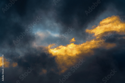 Stunning fluffy thunderstorm clouds illuminated by disappearing rays at sunset and dark thunderclouds floating across sky to change season weather. Natural abstract meteorology background.