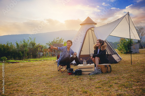 Young couples have good time morning on camping trip with sunrise background. Couples enjoy camping with morning coffee.