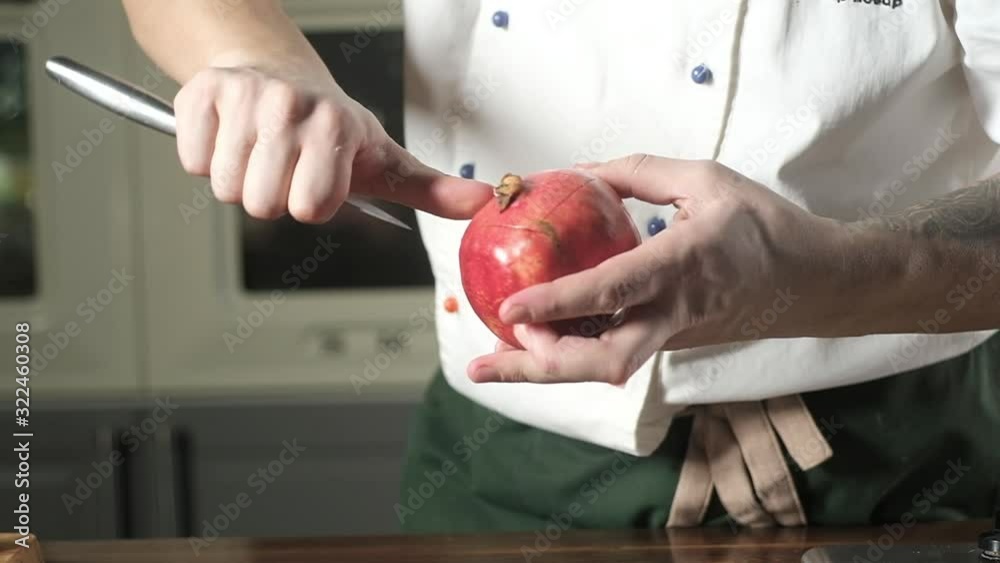 man in modern kitchen cuts rind of ripe pomegranate. vegetables and fruits. cook in kitchen prepares ingredients for delicious meal. preparing salad of fruits. dietary food. healthy product. man in modern kitchen cuts rind of ripe pomegranate. vegetables and fruits. cook in kitchen prepares ingredients for delicious meal. preparing salad of fruits. dietary food. healthy product.