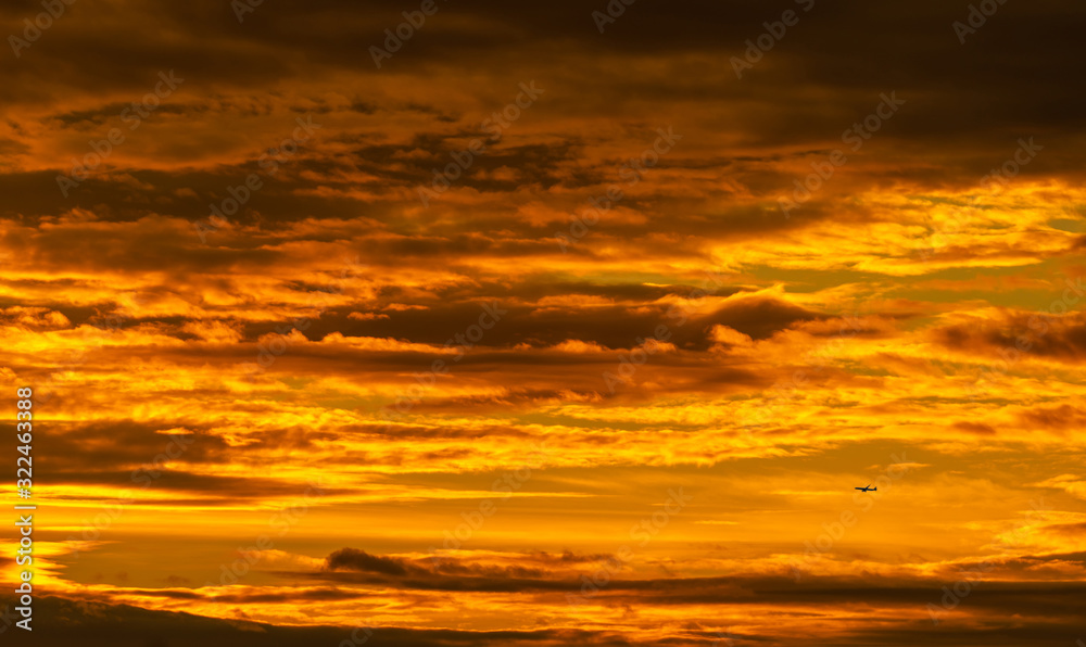 Silhouette small airplane flying on beautiful sunset sky. Golden vast sunset sky. Freedom and calm background. Beauty in nature. Powerful and spiritual scene. Dramatic and majestic golden sky.