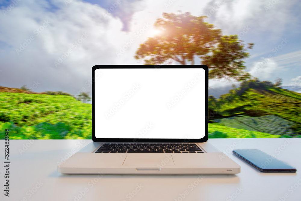 Fototapeta premium Laptop with blank screen on table with Coconut tree blur green nature in background. Technology concept.