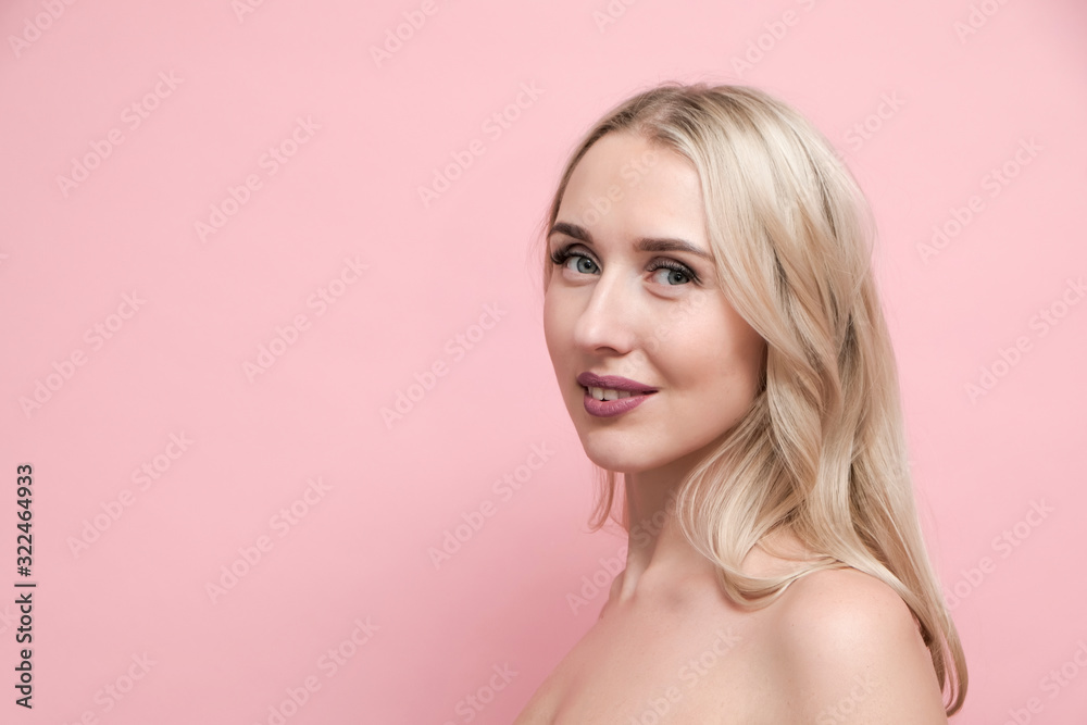 Beautiful blond woman with naked shoulders on pastel pink background. Beauty, cosmetics and skin care concept Beautiful blond woman with naked shoulders on pastel pink background. Beauty, cosmetics and skin care concept