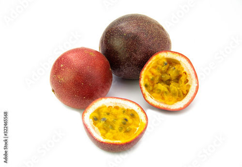 Two whole fresh tropical passion fruits and cut half isolated on white background