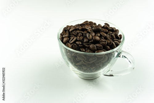Coffee beans inside clear glass over white background.
