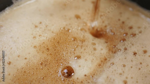 Dark beer is poured into a glass and beer foam is formed - shot in slow motion in extreme close up macro