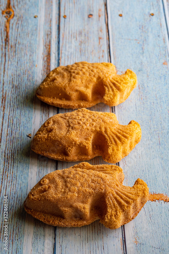 Traditional Malaysian cake called "kuih bahulu or baulu" in fish shape, over wooden background.