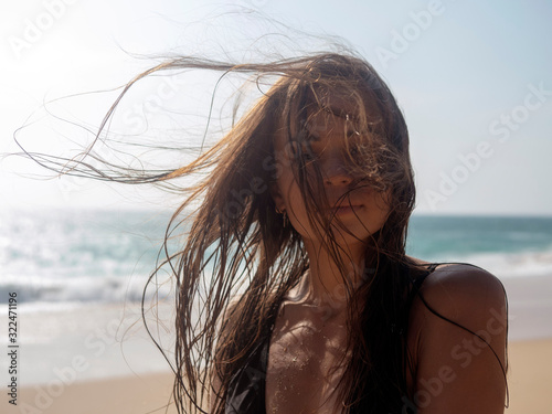 Portrait of a young woman with tangled hair from the wind against the background of the ocean