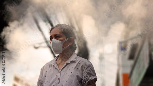 Old woman wearing mask against air pollution (PM2.5) in the city. PM2.5 caused health problem and respiratory system disorder as lung cancer, allergy, asthma, chronic obstructive lung disease(COPD). photo