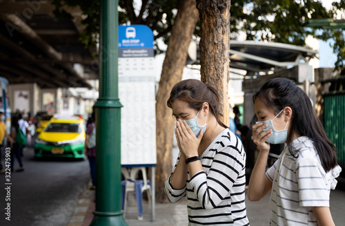Sick asian family,mother,daughter cough,sneezing,woman,child girl wearing protective mask have severe allergic reaction to dust,air pollution,smog,polluted environment from cars in the city street