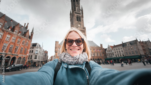 Woman takes selfies on a market square in Bruges, Belgium