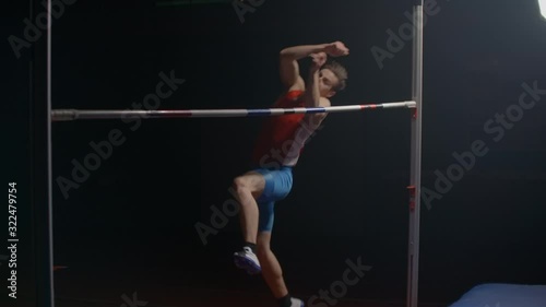 Olympic sport a man performs a high jump over a crossbar in slow motion.