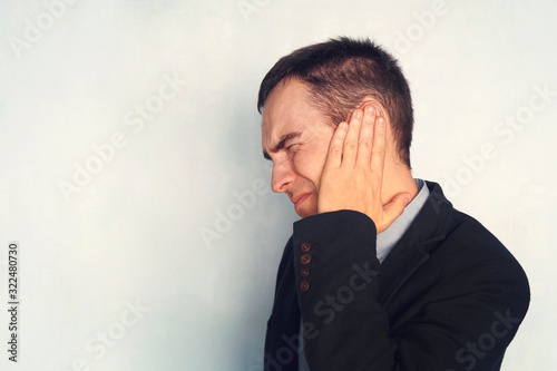 A businessman or working with tinnitus. Man with earache is holding his aching ear body pain concept. copy space photo