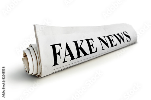 concept of false news. Rolled Up Newspaper with Headline of Fake News Isolated on White Background. photo