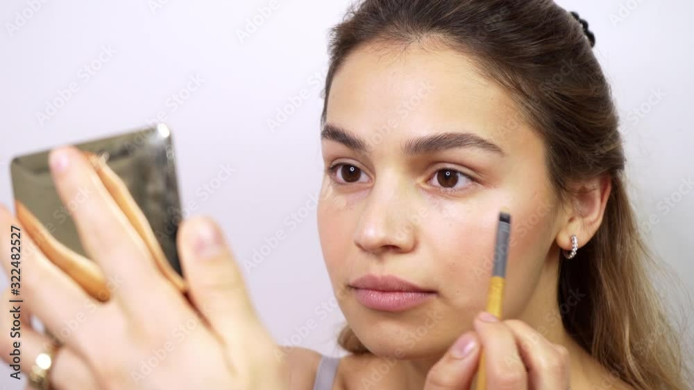 Beautiful mixed race young woman applying makeup. Confident and cute brunnete using makeup brush. Closeup portrait shot. Beautiful mixed race young woman applying makeup. Confident and cute brunnete using makeup brush. Closeup portrait shot.