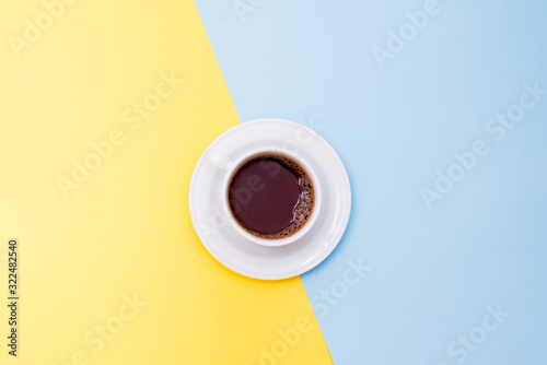 A cup of coffee on yellow and blue background with a copy space