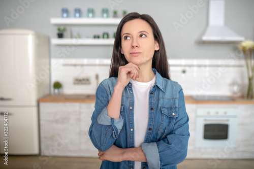 Free Download Thoughtful young woman standing in her kitchen - GFXLoad