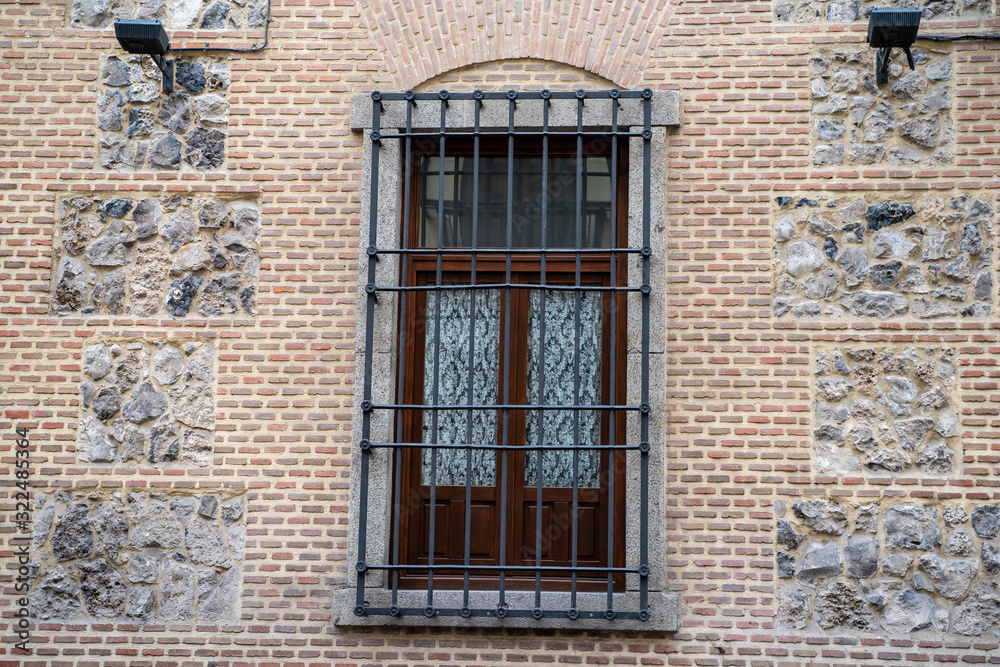 Interesting window and  wall brick facade with bars on window in Madrid Spain