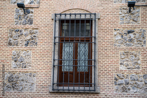 Interesting window and  wall brick facade with bars on window in Madrid Spain © MelissaMN