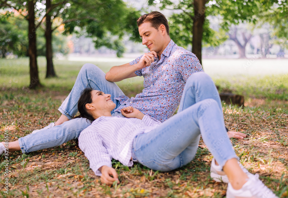 Obraz premium Couple young lover lying down on green grass in park together,Romantic and enjoying in moment of happiness time,Happy and smiling,Positive thinking,Eyes contact