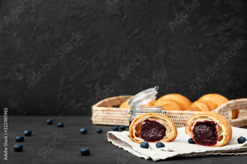 Tasty sweet croissant with jam on dark background