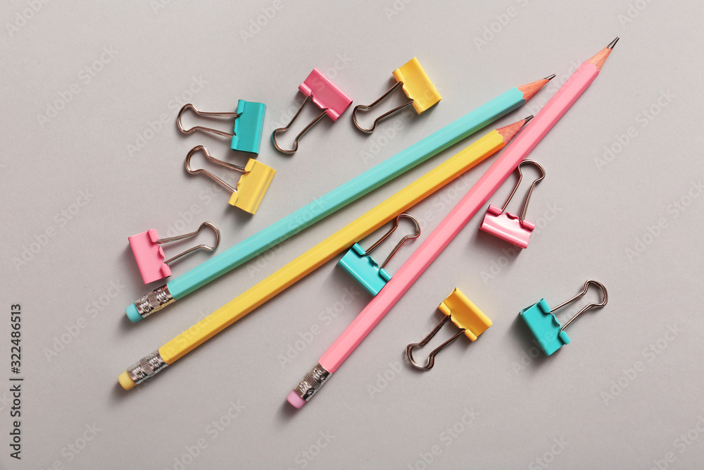 Binder clips and pencils on grey background Binder clips and pencils on grey background
