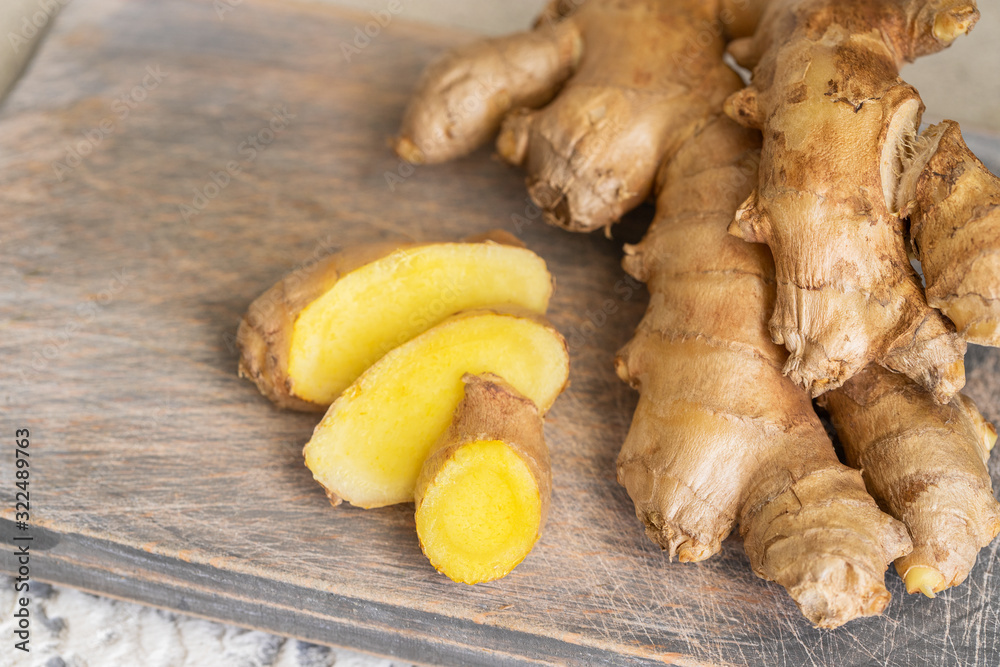 Ginger roots and ginger root sliced on cut board. Ginger used as spice for food and treatment in alternative medicine. Ginger roots and ginger root sliced on cut board. Ginger used as spice for food and treatment in alternative medicine.